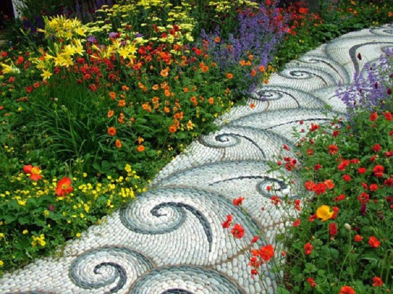 Mẫu thiết kế sân vườn với lối đi lát đá tạo hoạ tiết lạ mắt, 2 bên là hàng hoa nhiều màu sắc tạo không gian sinh động, tươi mới